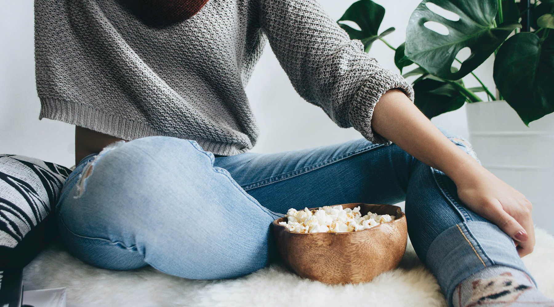 woman sits on a rug with a bowl of popcorn